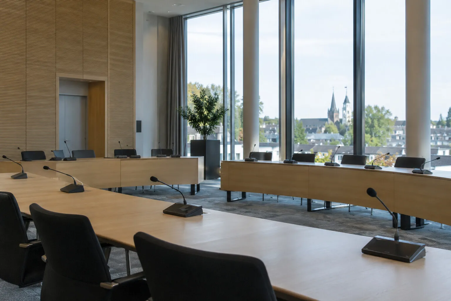 Lege raadszaal van een gemeentehuis met microfoons op de tafels