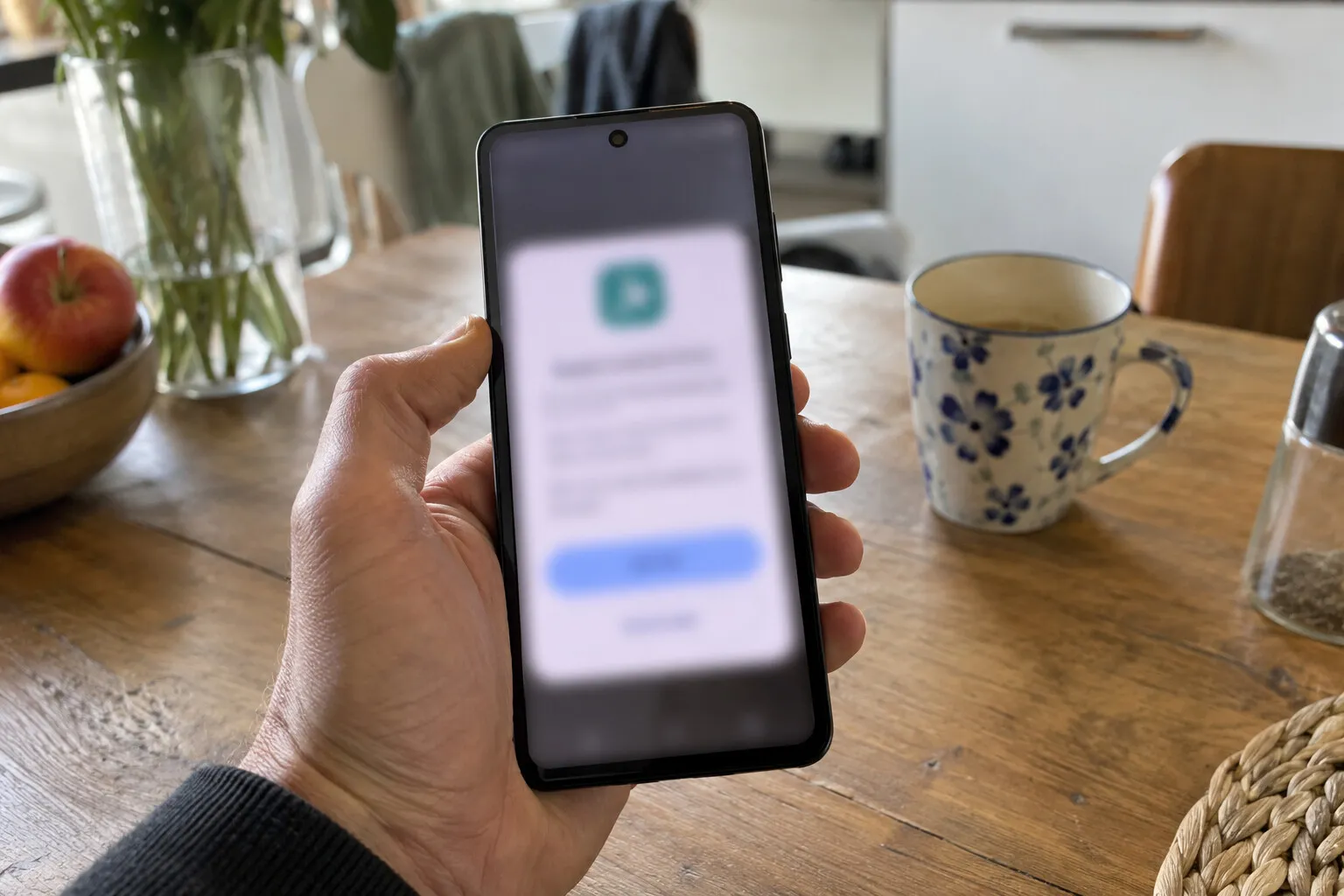 Hand houdt een Android-telefoon vast met een installatievenster van een app