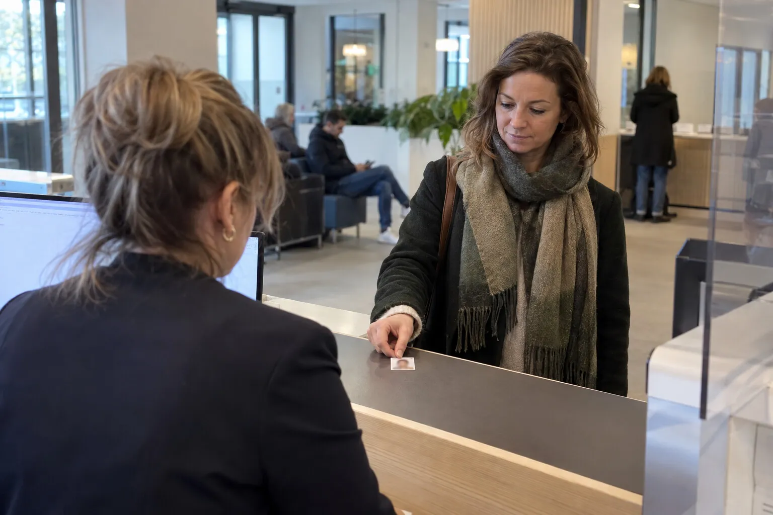 Vrouw legt een pasfoto op de balie van een gemeenteloket